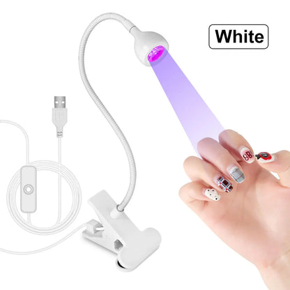 White UV/LED nail lamp with USB cable and clip, used on a hand with painted nails.