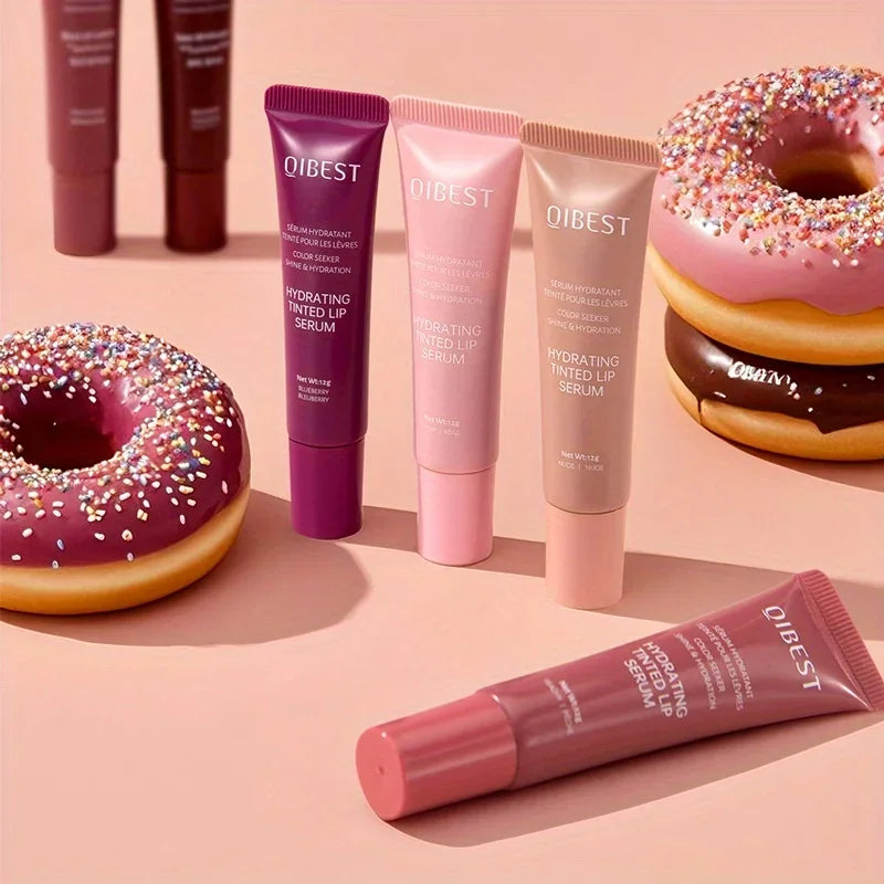Qibest lip serum tubes on a pink background with donuts. Coloured Lip Gloss 